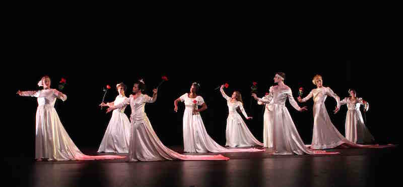 The young cast of Brides wearing white gowns and red roses in their hands